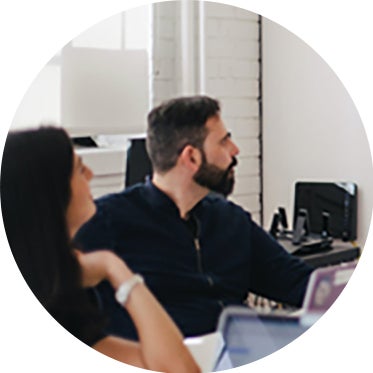 Partnering coworkers at table with laptops.