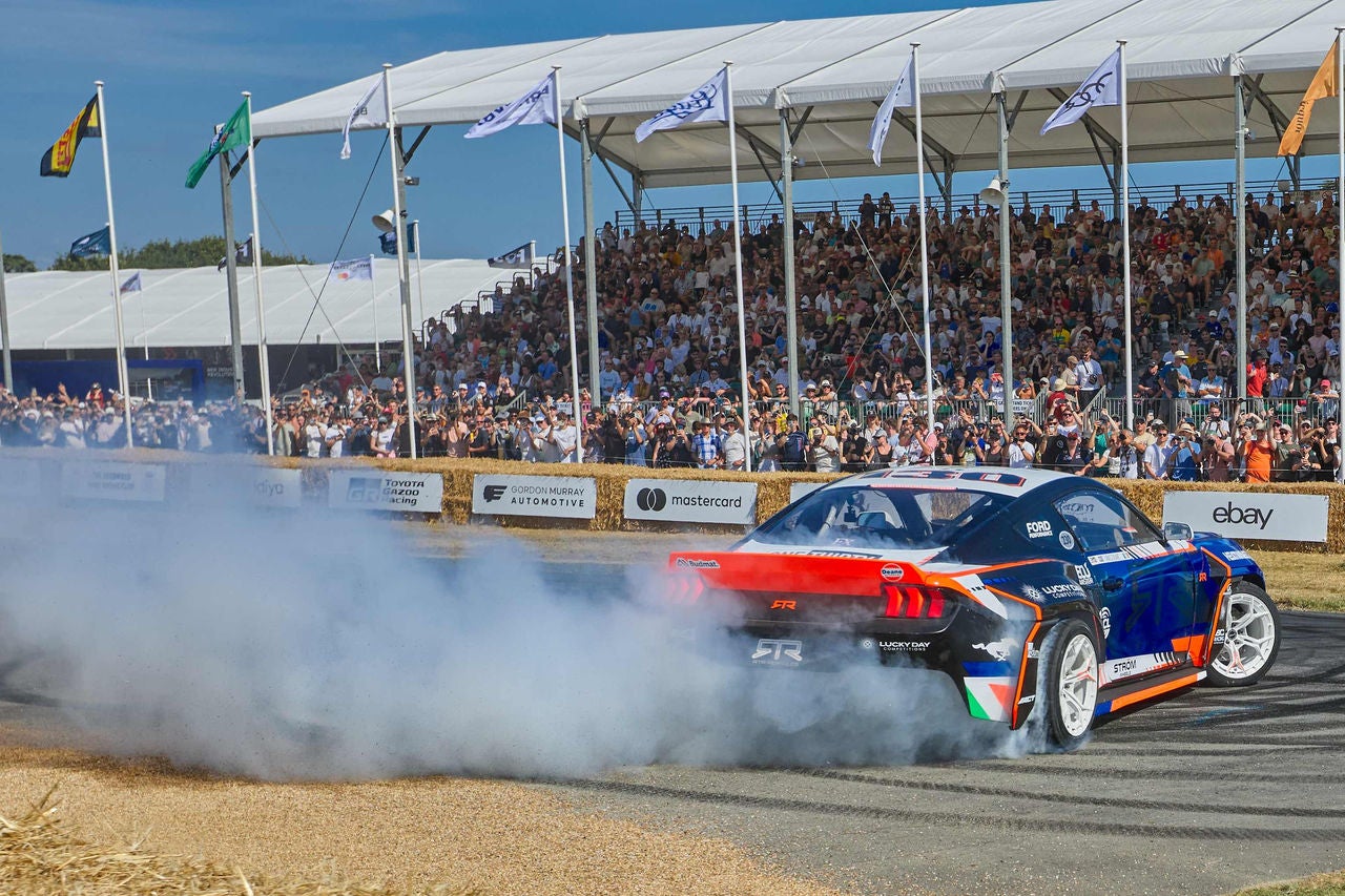 A race car billowing exhaust on the track at the Festival of Speed. 