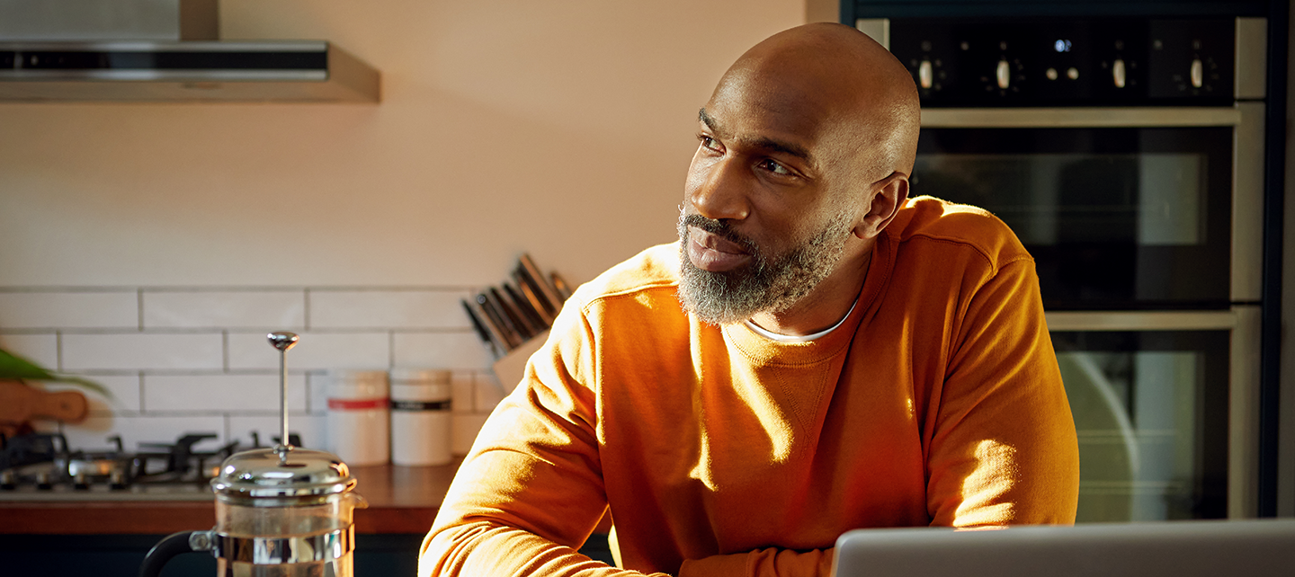 Man in his kitchen looking off into the distance