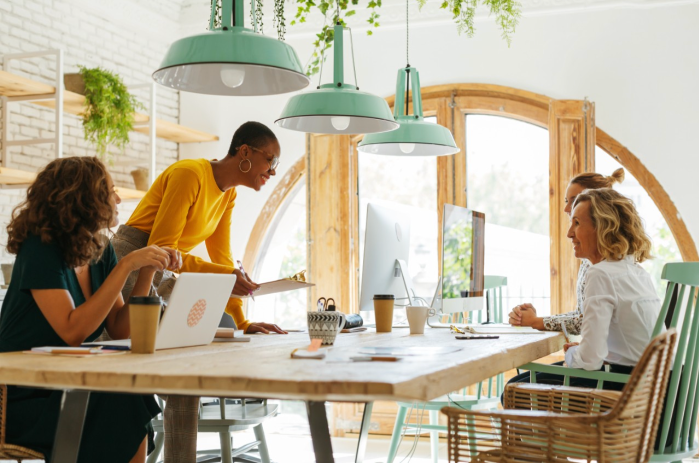 4 femmes à une table regardant des ordinateurs