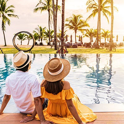 Tourist couple sitting near a luxury swimming pool.