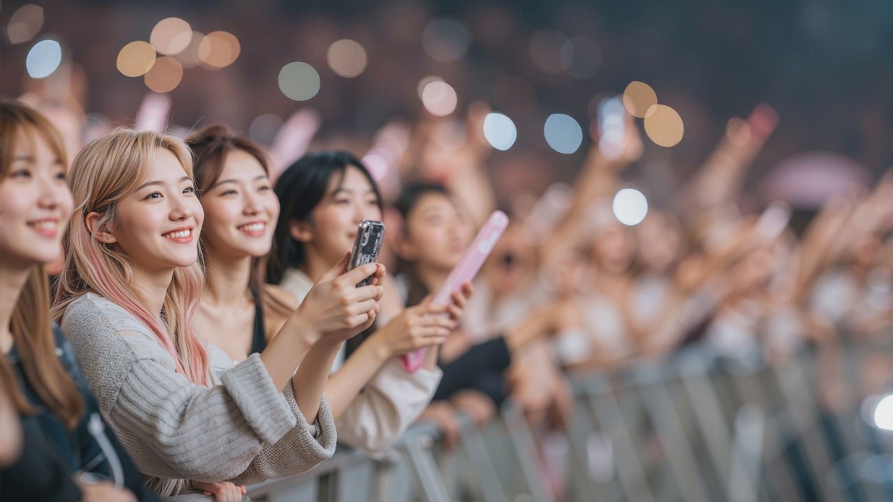Young woman holding phones stand in front of a stage. 