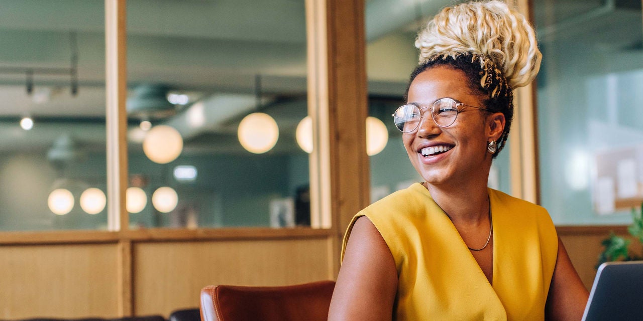 Woman in yellow shirt smiling at the office
