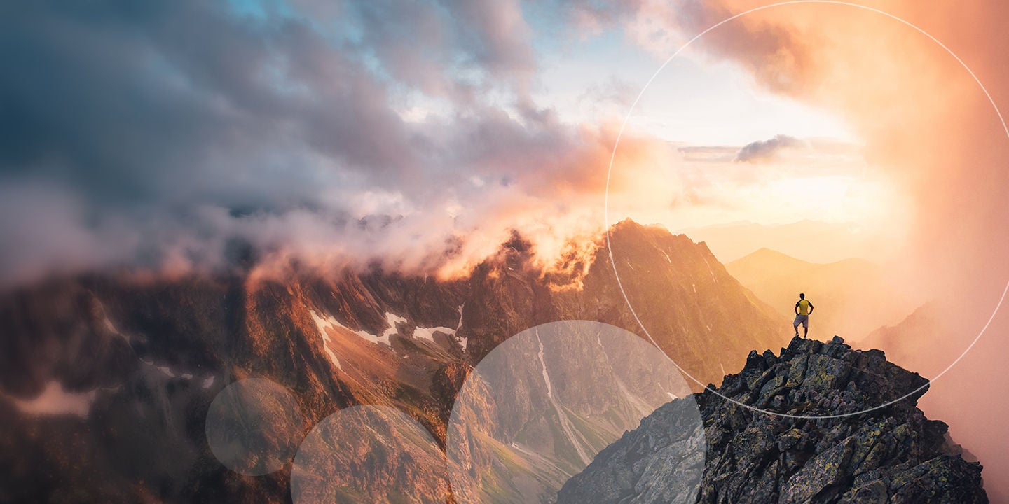 A man stands triumphantly on a mountain peak, encircled by a faint circle, showcasing his achievement in nature.