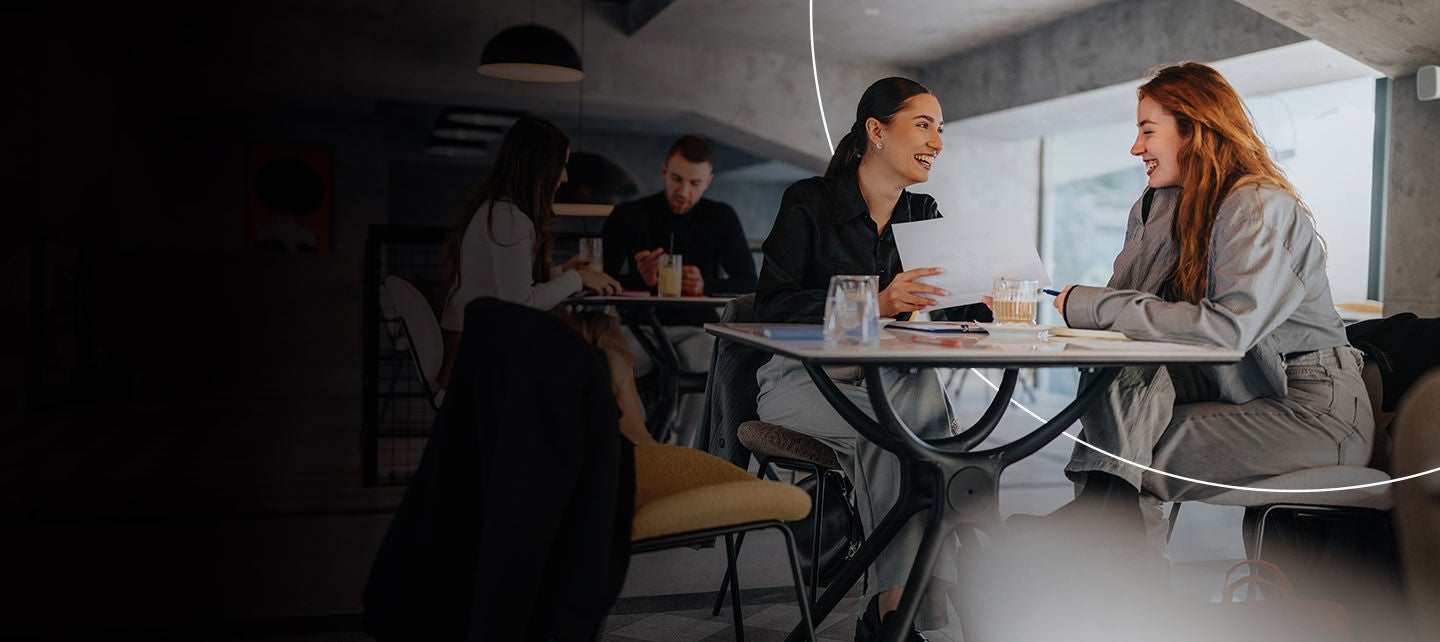 Dvije žene se smiju zajedno dok sjede na kafi.