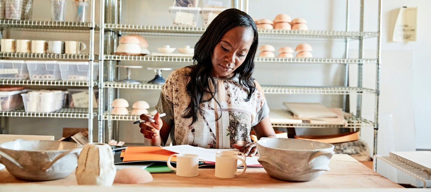 A woman looks over paperwork in her pottery studio. 