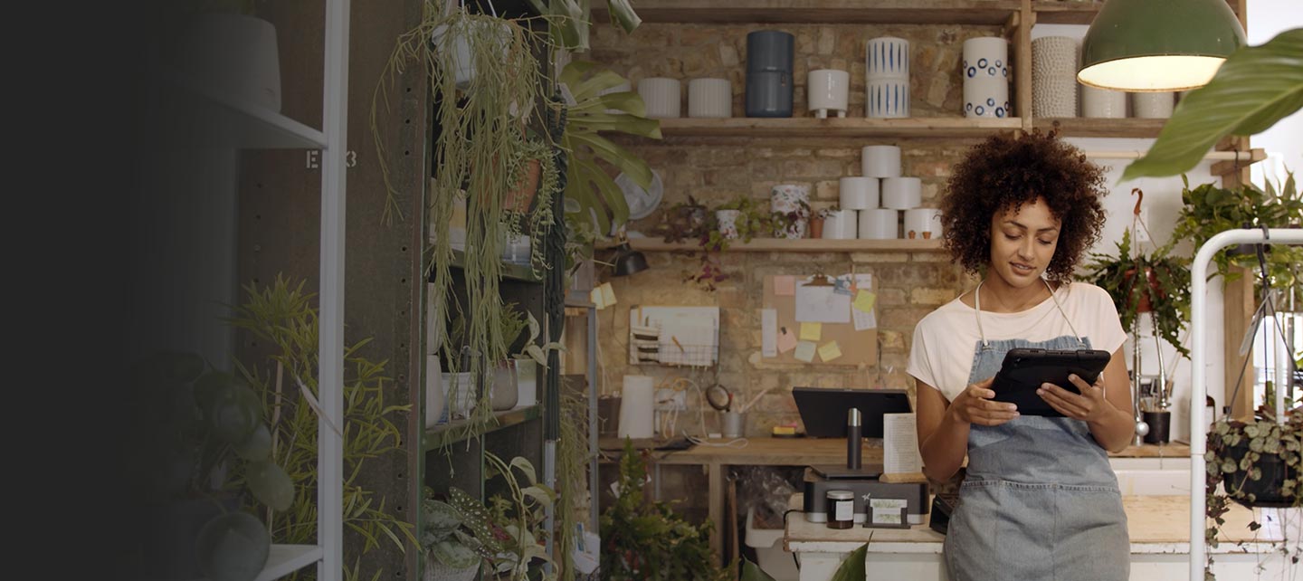 Female business owner checking orders online on a tablet at her store.