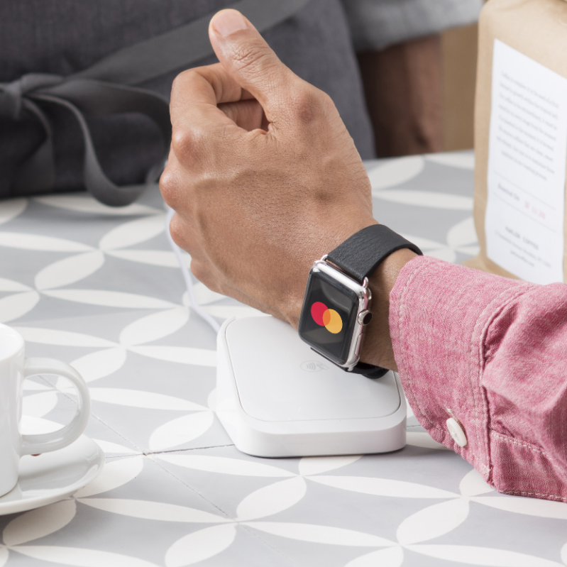 Man's arm with a smartwatch displaying Mastercard's logo
