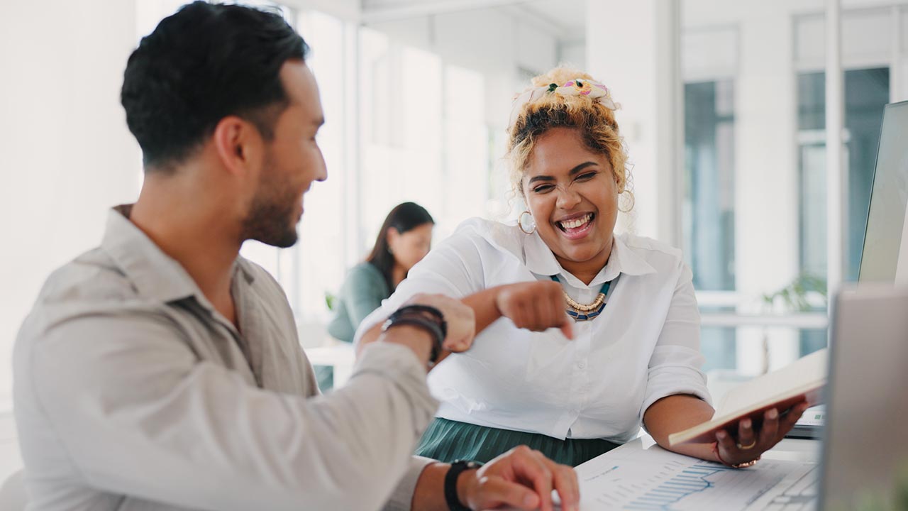 Two colleagues celebrating at a desk.