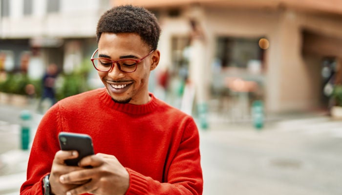 Mann in einem roten Pullover, der ins Telefon lächelt