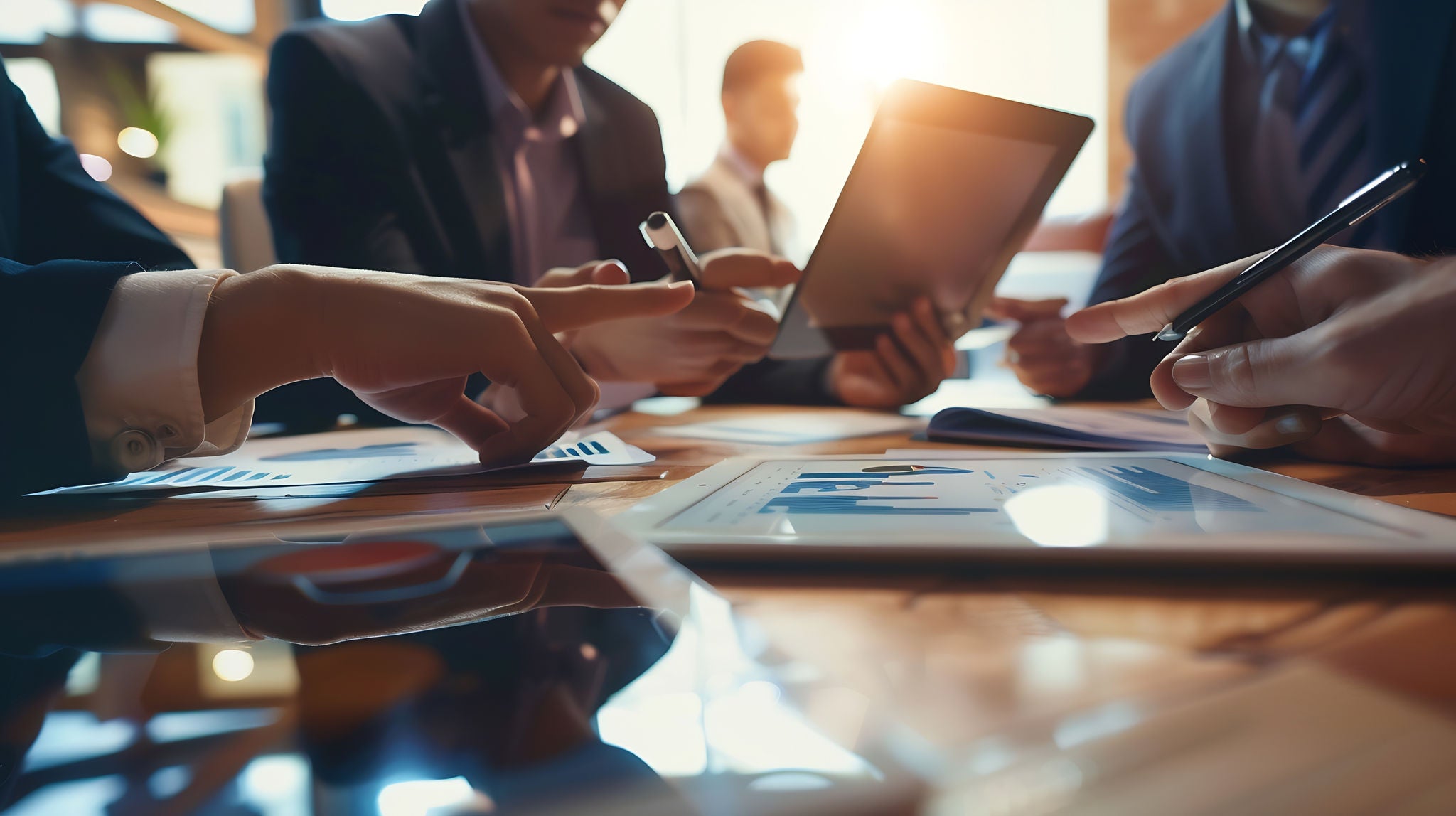 Close shot of hands working on tablet device at a conference table.