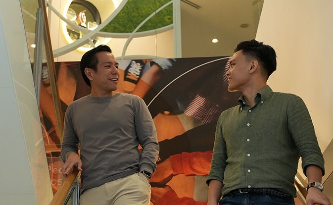Two men talking near a staircase indoors.