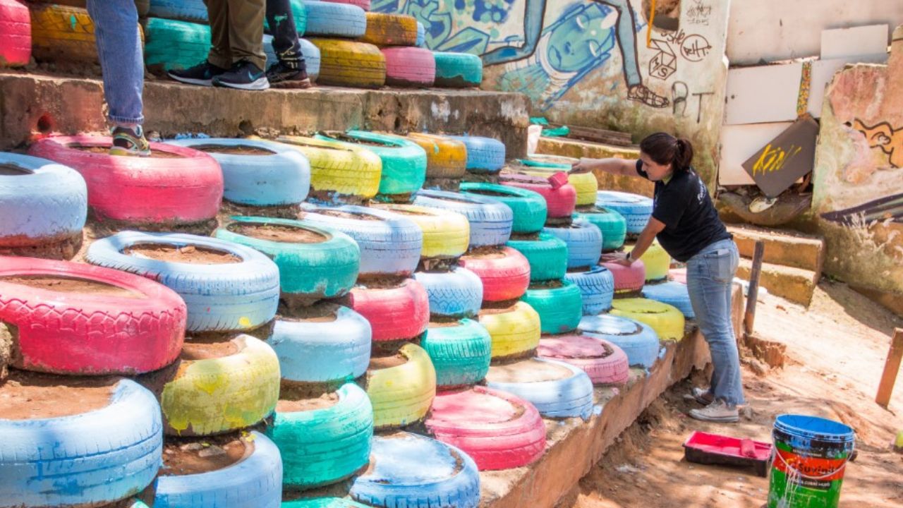 Rita Krejici paints tires stacked as a retaining wall . 