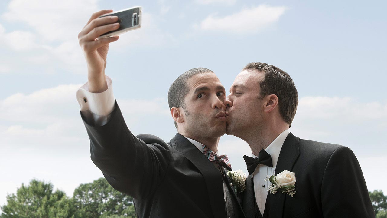 Two men in dress suits taking a selfie.