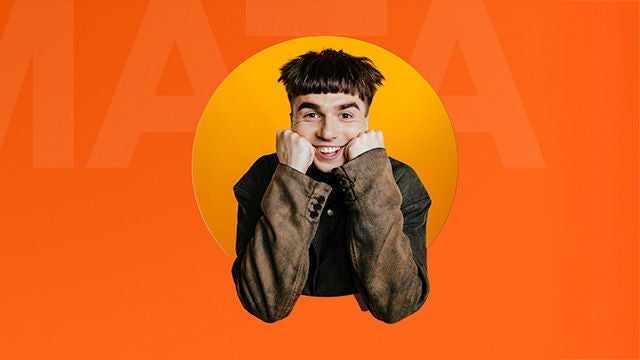 Uśmiechnięty młody mężczyzna pozuje na pomarańczowym tle.