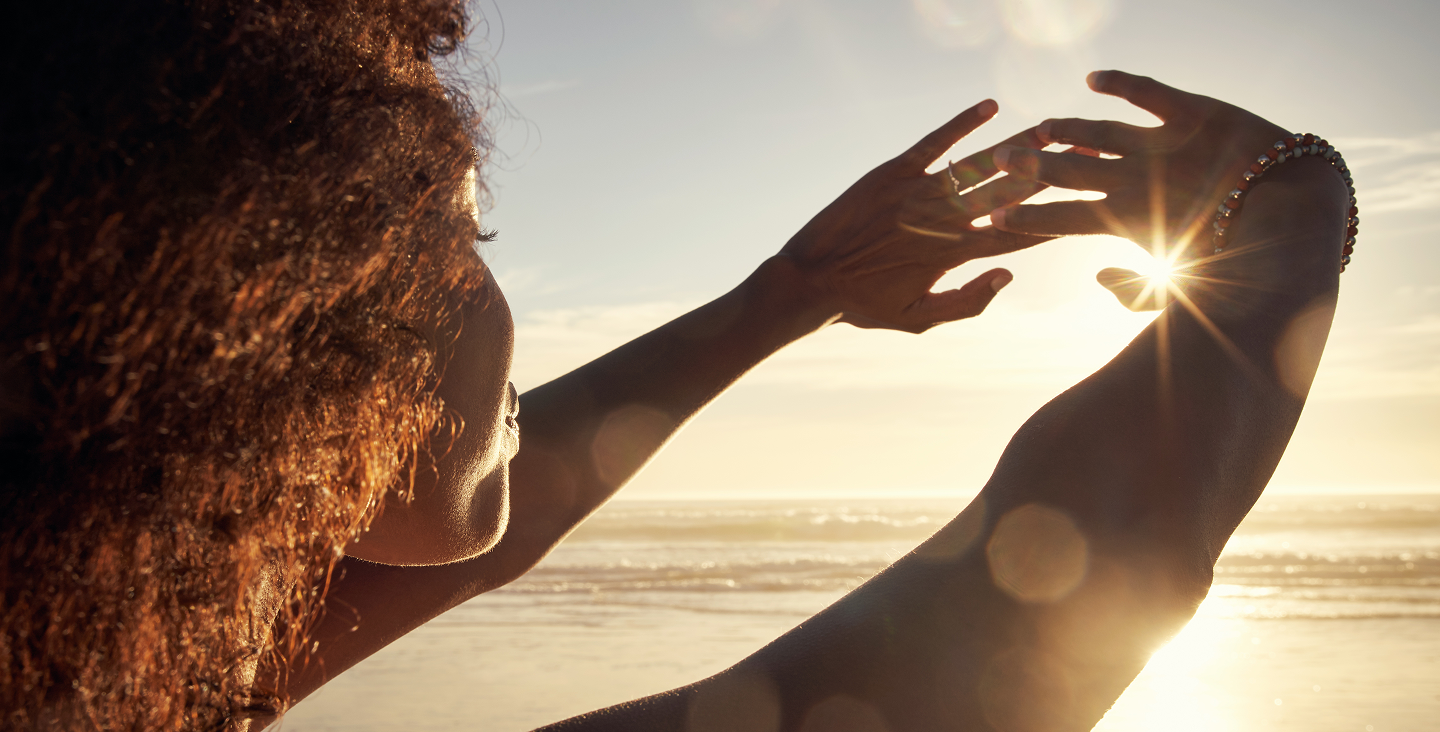 Woman holding her hands up to a sunset