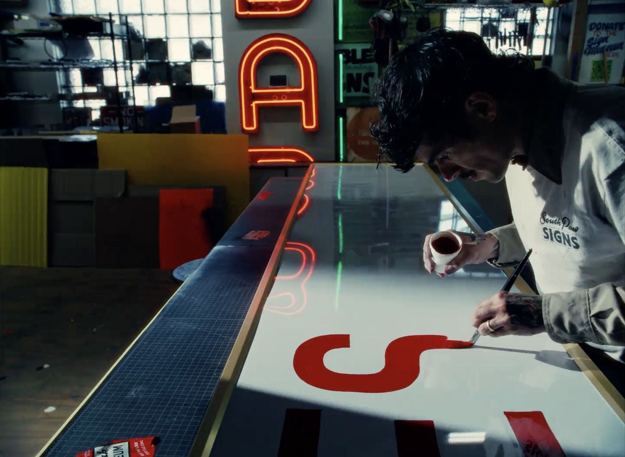 A man paints a sign.