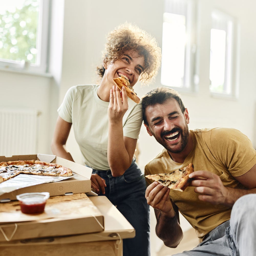 ragazzo e ragazza che mangiano pizza ridendo