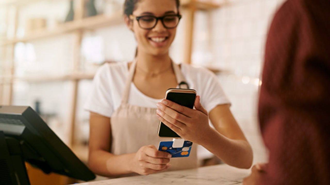woman using phone at pos terminal.