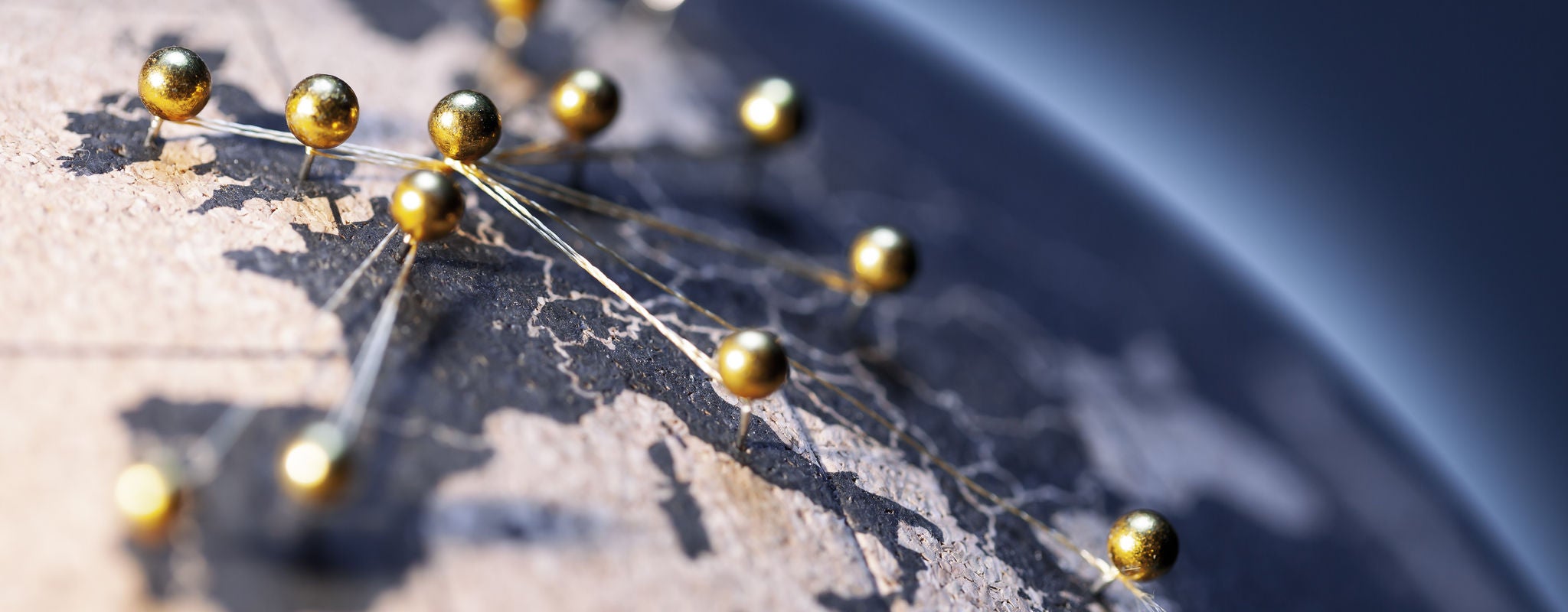 Close-up of a globe with gold pins connected by threads, highlighting a network across Europe.