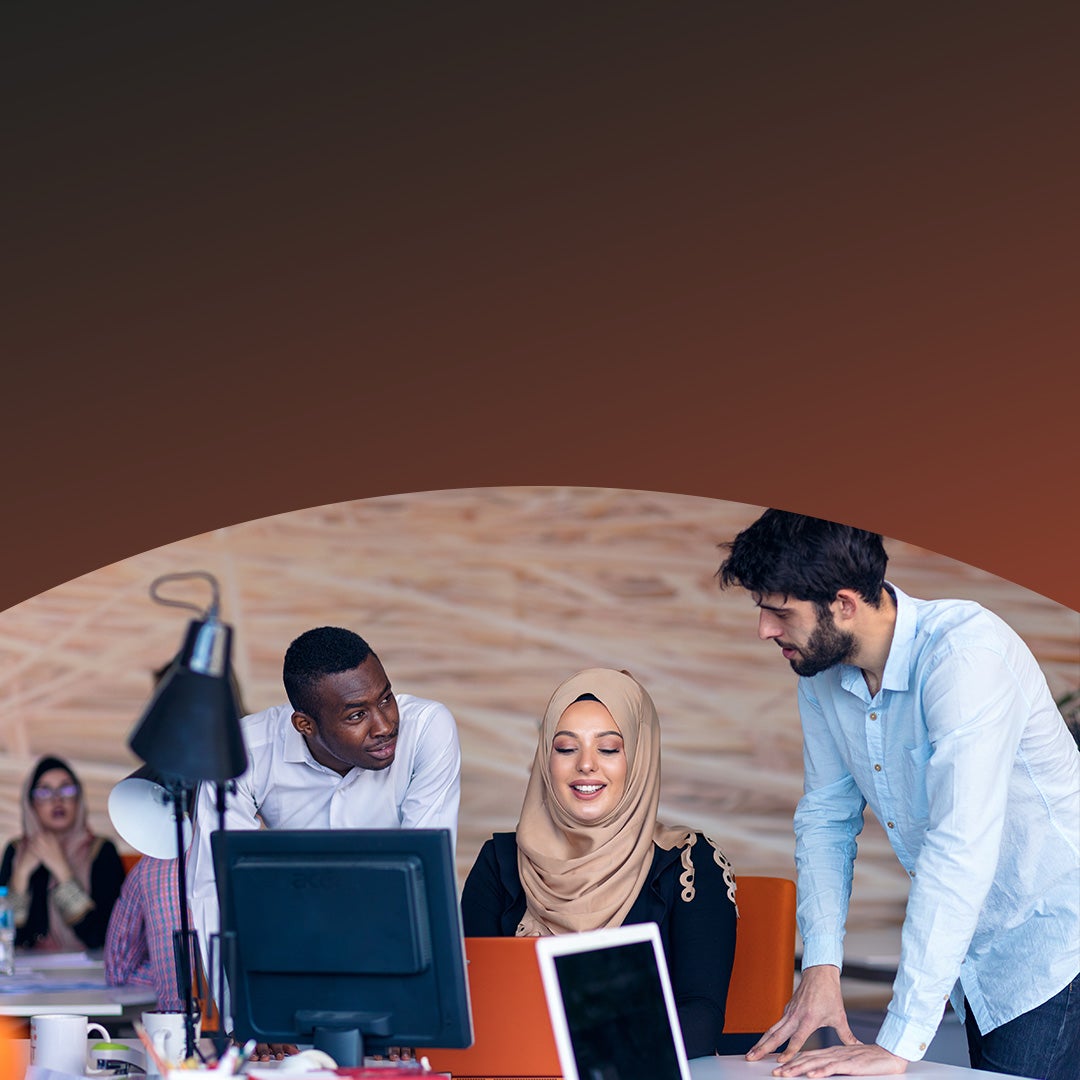 Tres compañeros de trabajo colaborando en un escritorio. 