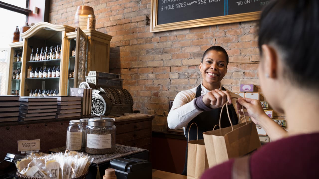 smiling woman giving package in a shop