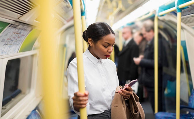 Woman riding subway and looking at her phone.
