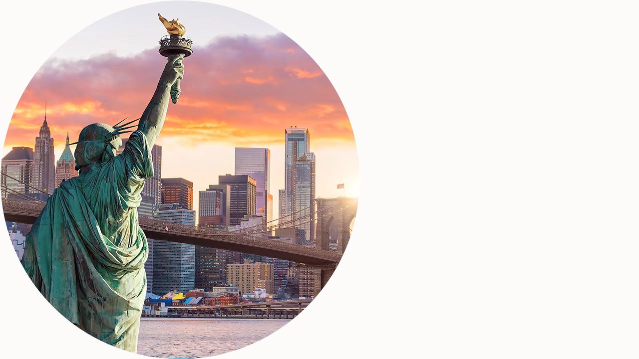 Statue liberty and New York city skyline at sunse.