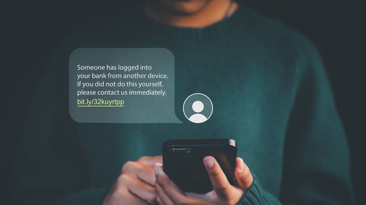 A person holds a smartphone with a scam text on it. 