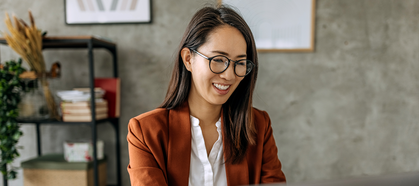 Woman happily doing work in the office on her laptop