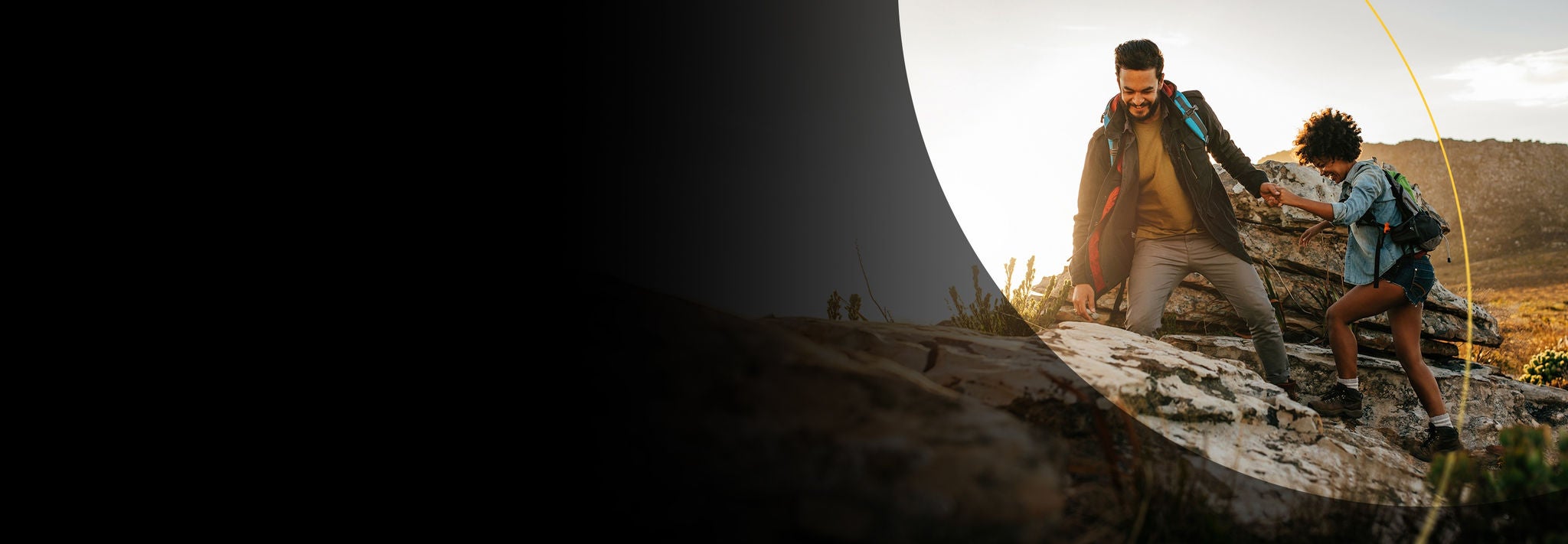 Man helping a woman up a rock hiking