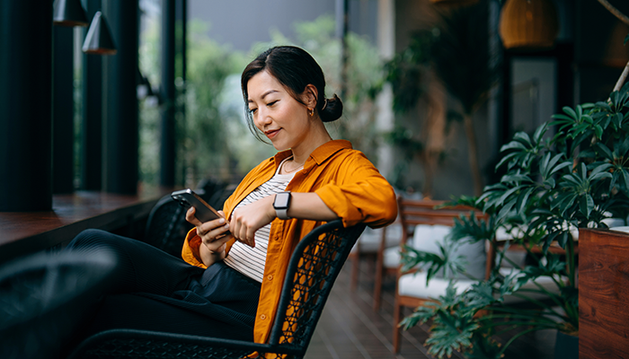 Woman outside sitting on a chair on phone