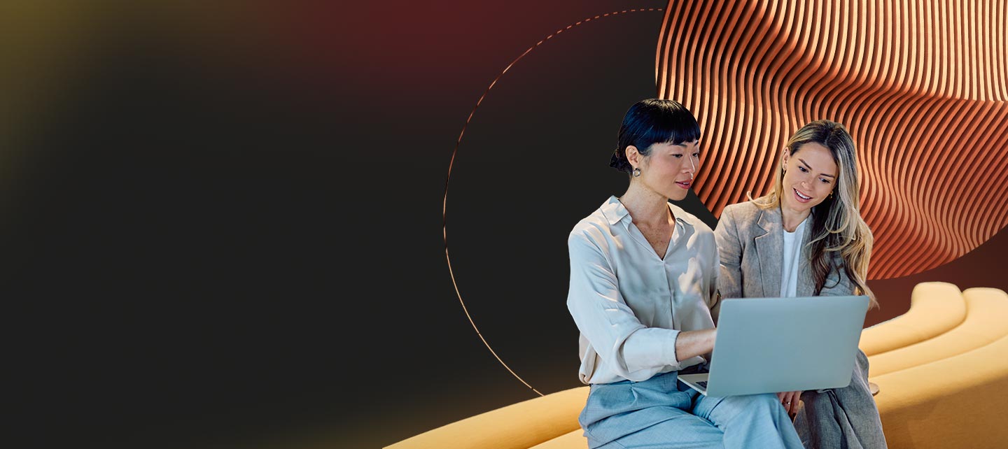 Two women sitting on bench with laptop and abstract background