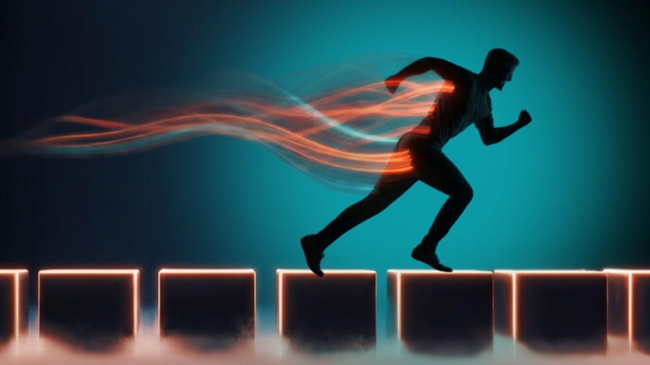 A silhouette of a man running over boxes with red and green light trails coming off him. 