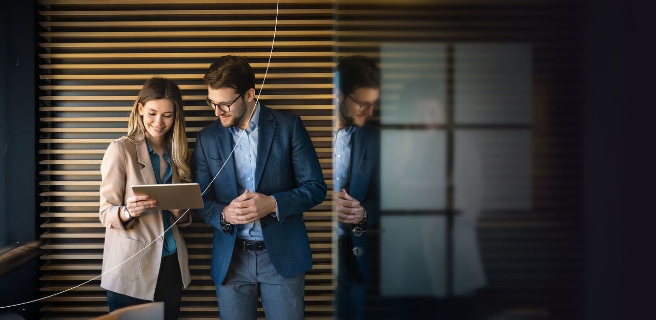 שני אנשים מנהלים דיון תוך כדי צפייה בטאבלט בחלל משרדי.