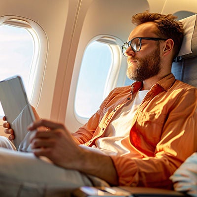 Man sitting with tablet in airplane.