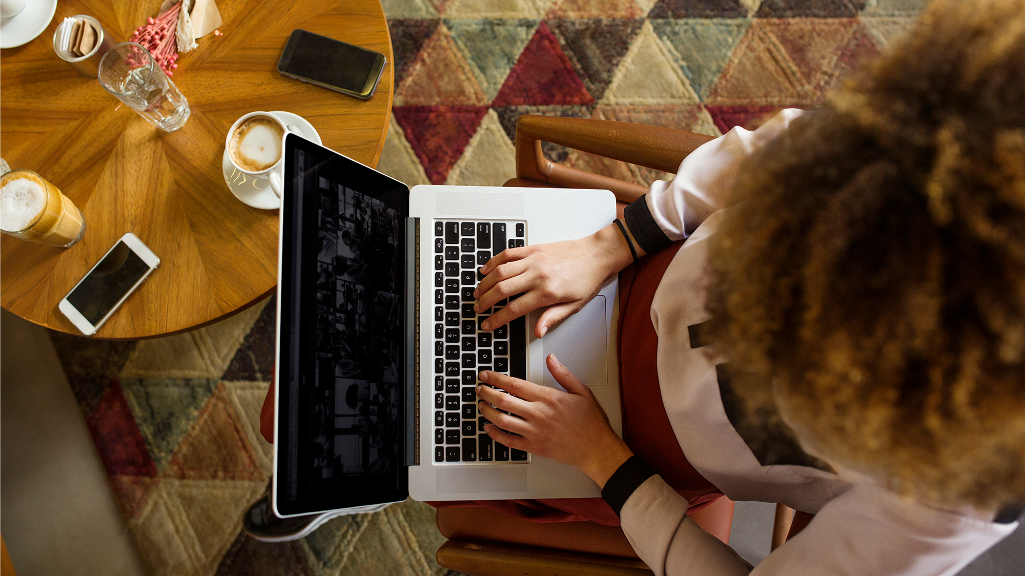 Aerial view of a woman typing on a laptop computer in a cafe.