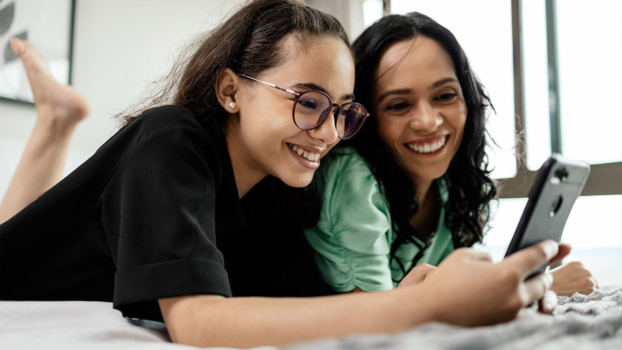 Mother and teenage daughter using smartphone