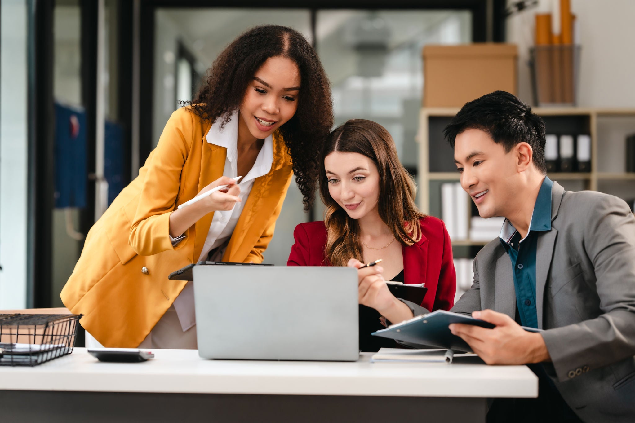 Two women and a man looking at a laptop screen.