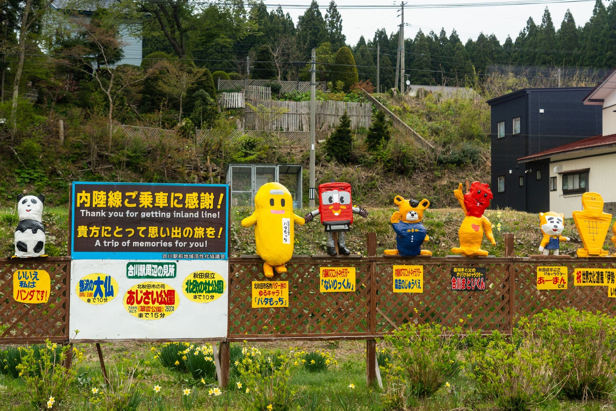 Cute 3-D images of animals, trains and other figures lign a fence with signs in Japanese and English thanking people for riding the Smile Train. 