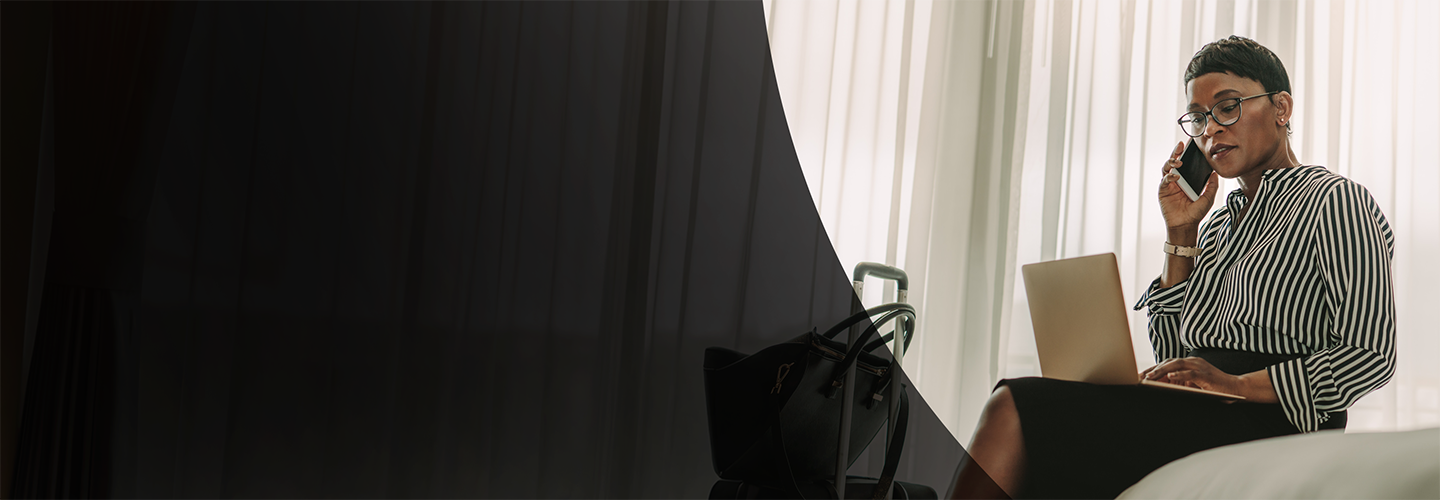 Frau am Telefon schaut auf ihren Laptop im Hotel