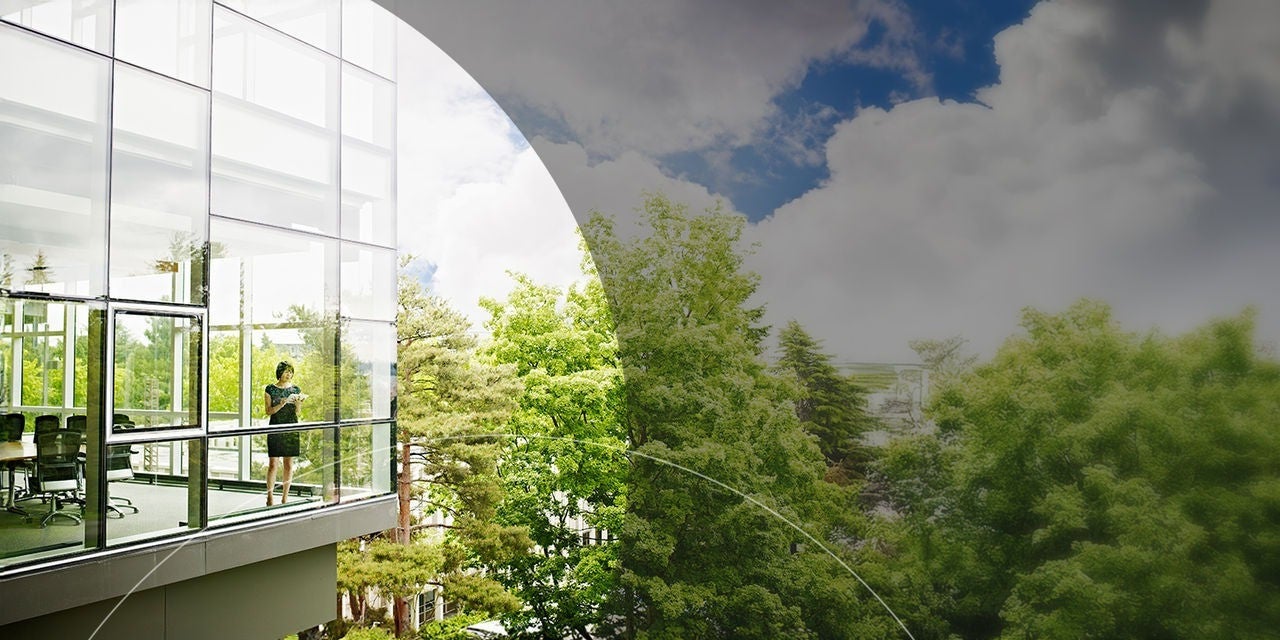 امرأة تقف داخل مبنى زجاجي للمكاتب.