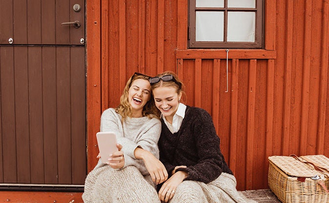 to venner som ser på en telefon og ler.