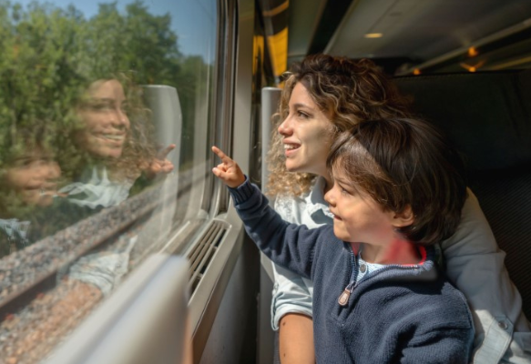 A woman and her son look out a train window.