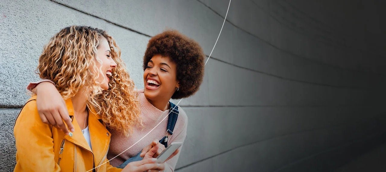 שני אנשים מחייכים נהנים מהיתרונות של מחזיקי כרטיס Mastercard.