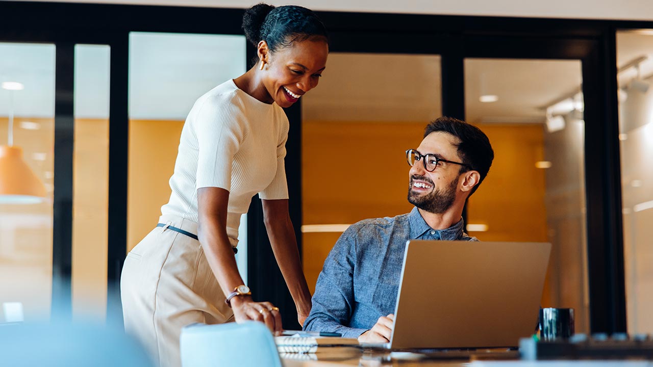 Two coworkers smiling and talking about work