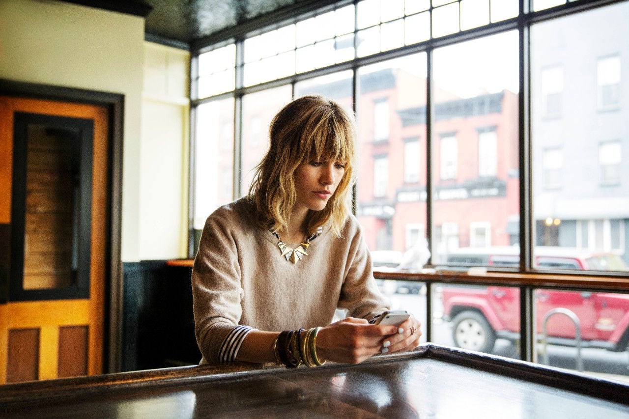 A woman on her phone looking out of a cafe window