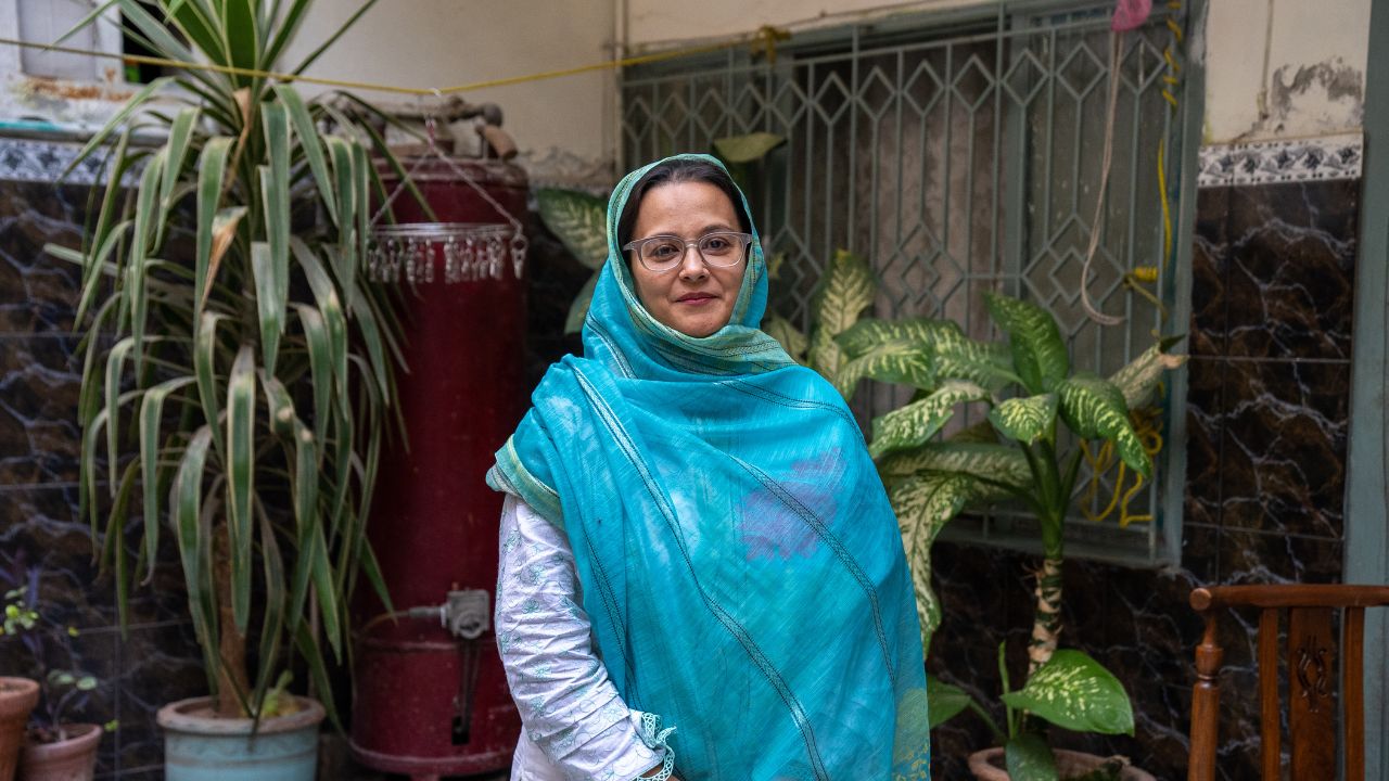 Babra Zafar smiles outside near potted plants. 