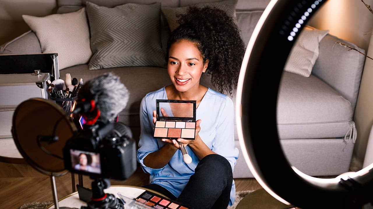 Female vlogger showing cosmetic accessories.