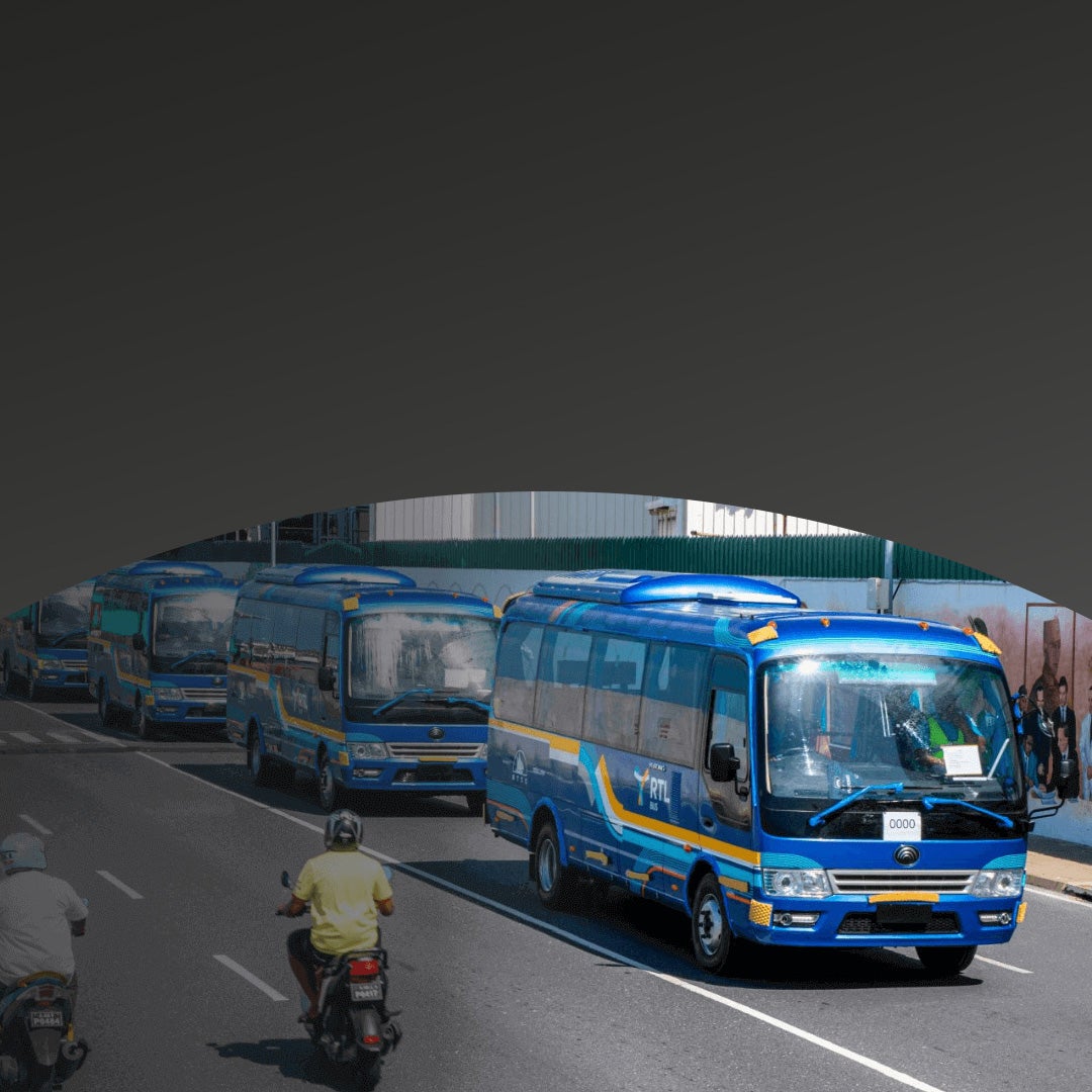 Several blue and yellow minibuses drive in a line on a city street, with motorcyclists riding nearby.